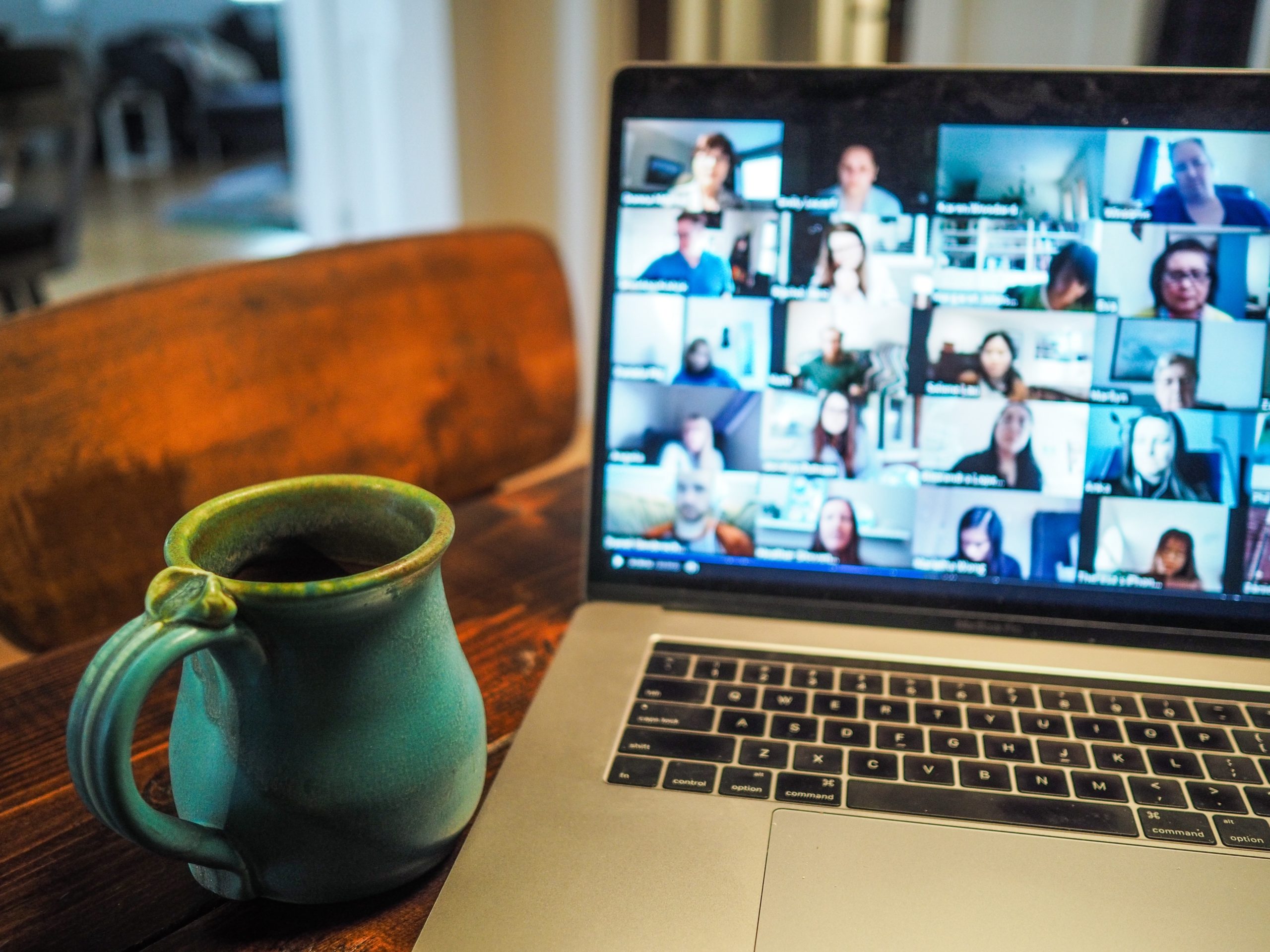 Un ordinateur avec le logiciel Zoom ouverte et une tasse